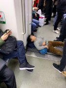 小男孩头枕书包手搭皮球 仰面躺在车厢连接处