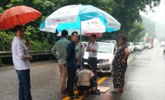 摩托车司机摔倒在地 小贩拿大伞为他遮雨