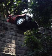 重庆一小轿车撞倒围墙   车头悬空
