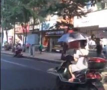 厉害了我的姐  女子一边骑车一边打伞