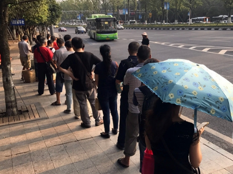 近期，重庆气温偏高。即使这样，出行的市民，依旧排队乘车。会展中心188路公交站，20多名乘客排着长长的队伍等车，阳光从树叶的缝隙中照在乘客身上，一些乘客撑起太阳伞遮挡刺眼太阳。