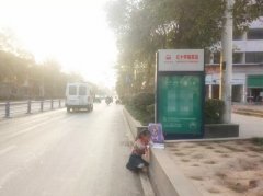 小女孩公交站台写作业  身后还有车辆经过