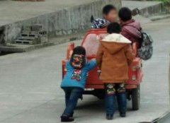 小孩骑着三轮在路上飞奔  嘴里还吃着棒棒糖