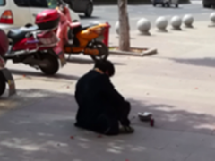 男子街头盘腿而坐  如此求助引质疑