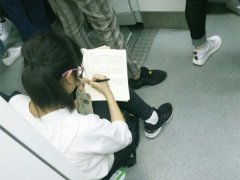 女孩蹲坐在车厢连接处写字 网友：想起自己小时候