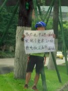 男子路边举牌求饭钱  路人质疑其身份
