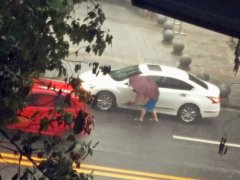 男子雨中撑伞洗车 网友直呼“太会过日子”