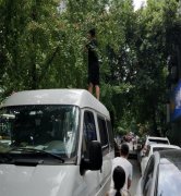 黑衣男子不顾安危  站在车顶摘果子