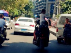 男子驾摩托道路上行驶 女孩站在后座上左顾右盼