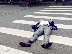 男子斑马线上倒地  右手握拳捂肚左手举着