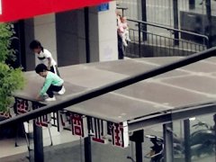 两小孩在玻璃棚上“走秀” 路人很担忧