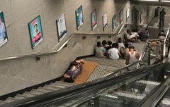 大妈轨交站内自带凉席 赤脚靠墙睡觉
